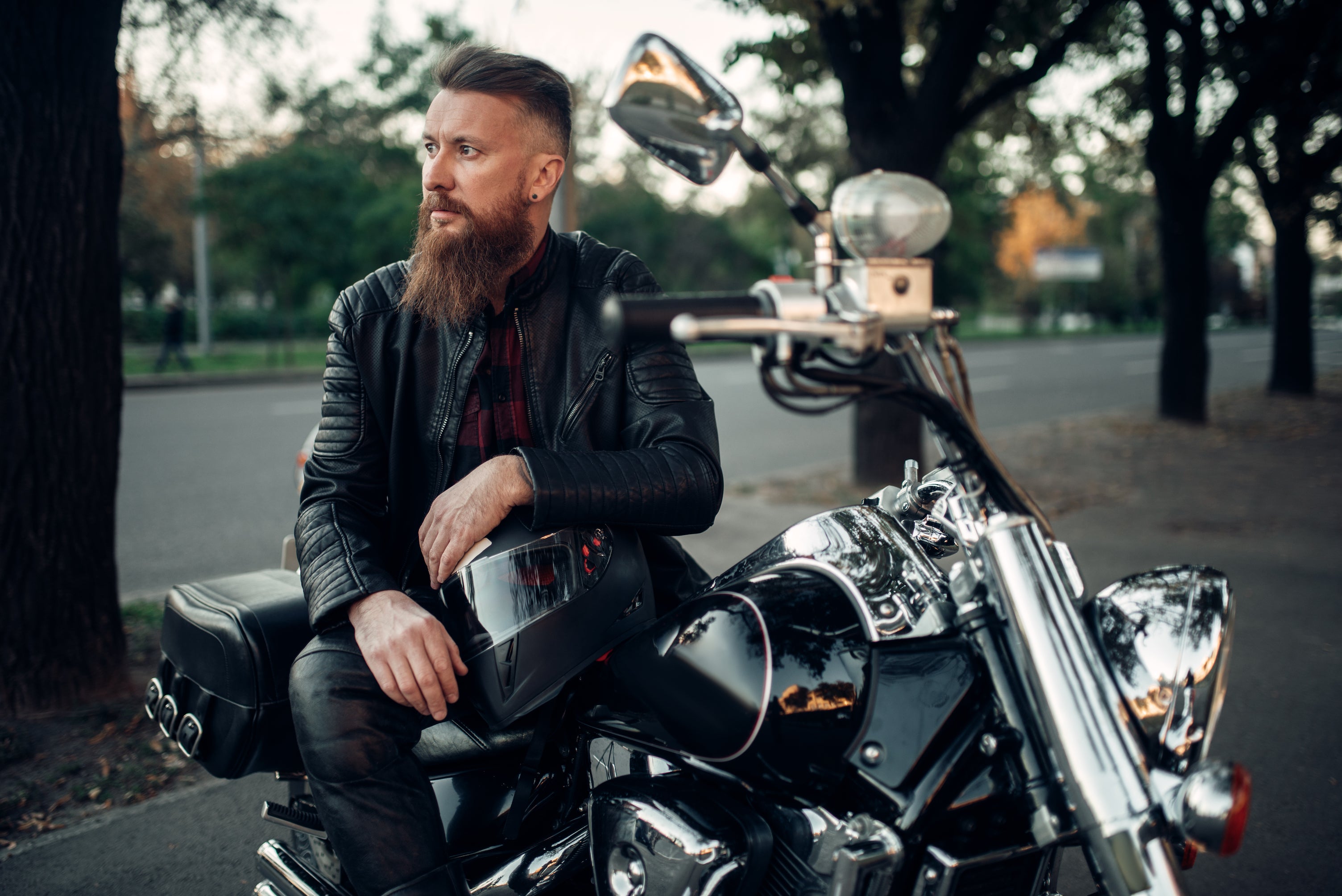 baerded-biker-poses-on-chopper-leaning-on-a-helmet